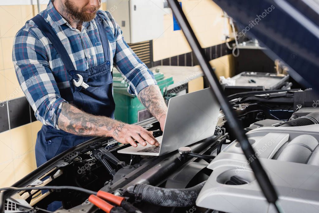 Mechanik podłączający komputer diagnostyczny do samochodu
